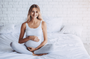 Jolie femme enceinte est assise dans son lit